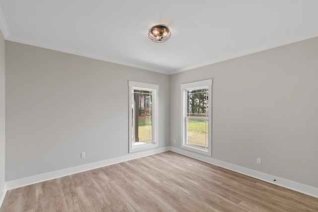 spare room featuring crown molding, light wood-style floors, and baseboards