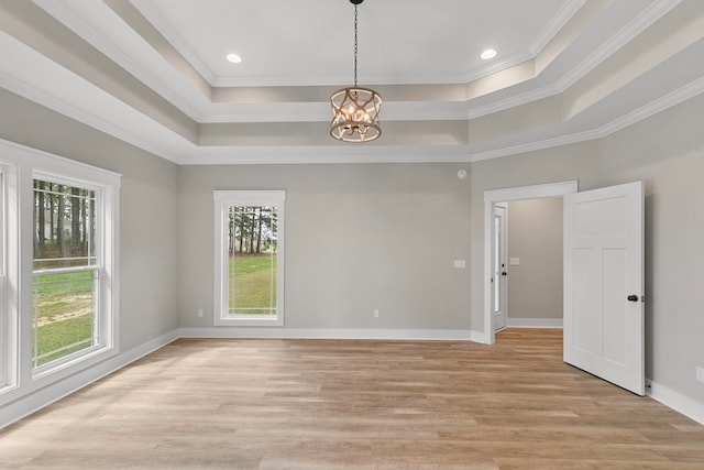 empty room featuring a raised ceiling, a notable chandelier, and plenty of natural light