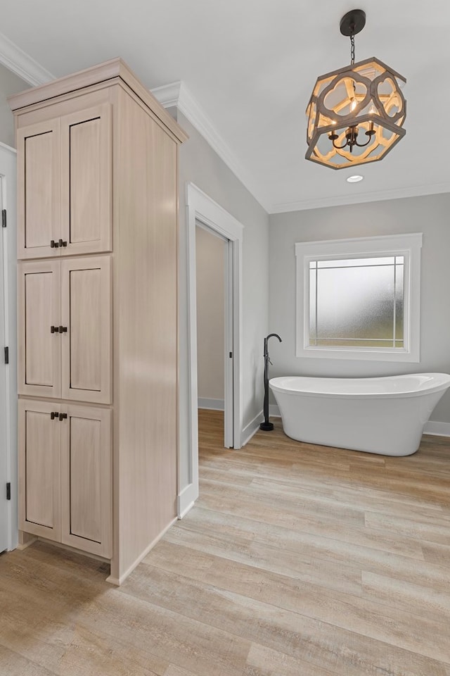 full bath featuring a freestanding tub, ornamental molding, a chandelier, and wood finished floors