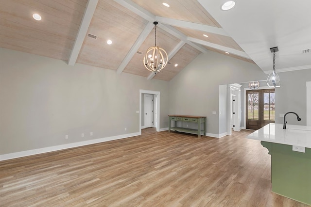 unfurnished living room with beam ceiling, french doors, light wood finished floors, an inviting chandelier, and baseboards