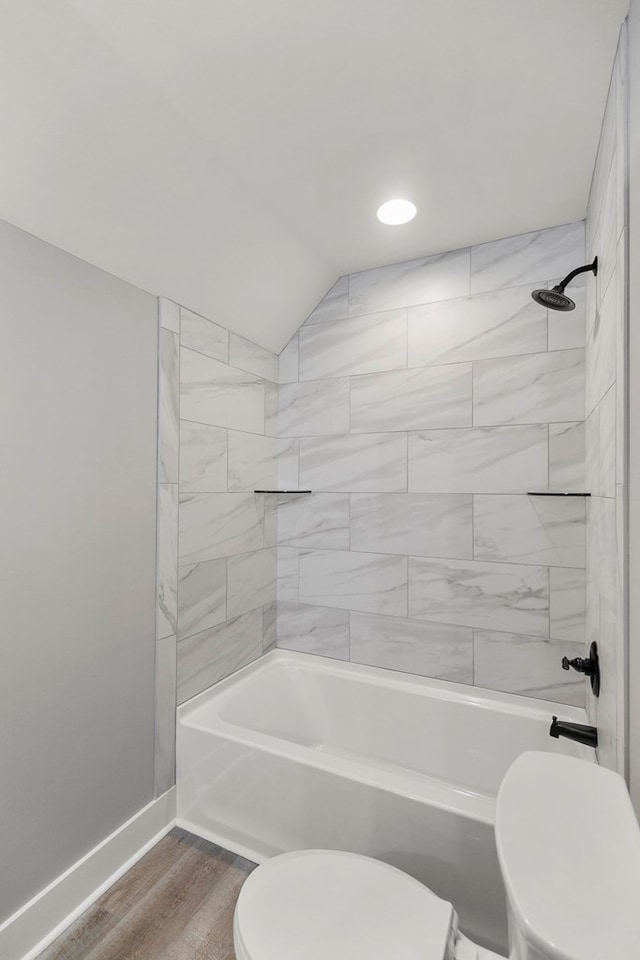 bathroom featuring baseboards, shower / bath combination, toilet, and wood finished floors