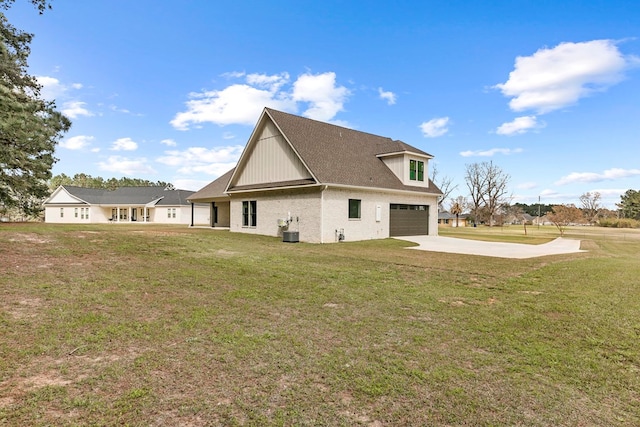 rear view of house with brick siding, concrete driveway, a lawn, an attached garage, and cooling unit