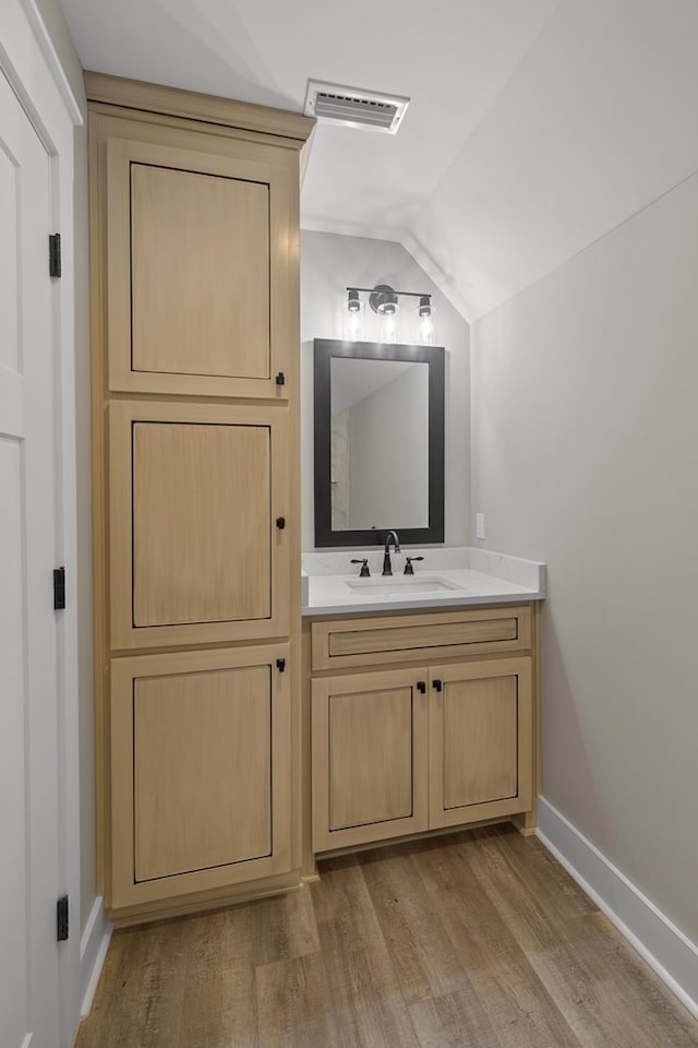 bathroom with visible vents, vaulted ceiling, vanity, and wood finished floors