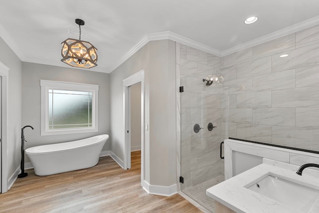 full bath with a freestanding tub, wood finished floors, a sink, ornamental molding, and a stall shower