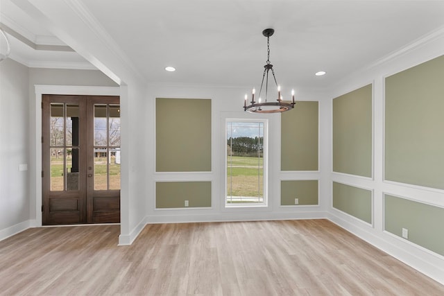 unfurnished dining area featuring a chandelier, ornamental molding, and wood finished floors