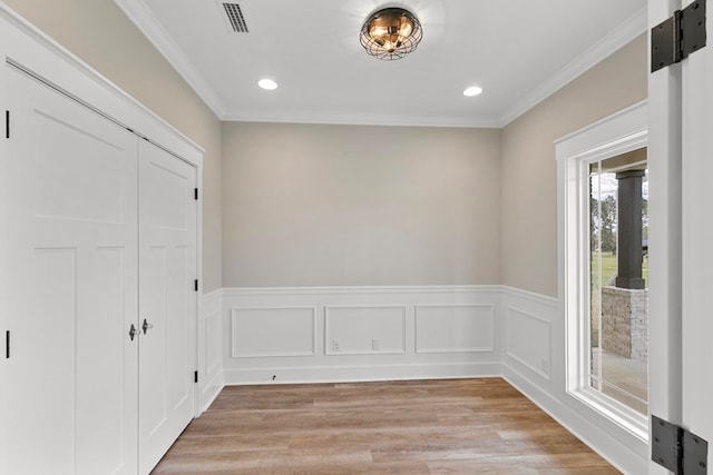 empty room with visible vents, crown molding, and light wood-style flooring