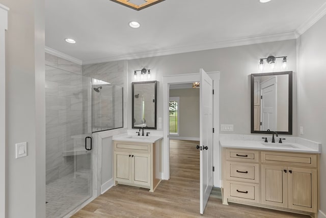 full bathroom featuring ornamental molding, a sink, a shower stall, and wood finished floors