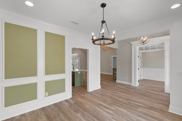 unfurnished dining area featuring ornamental molding, light wood-style floors, visible vents, and a notable chandelier