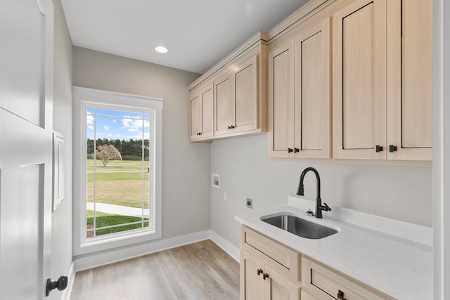 laundry area with cabinet space, baseboards, light wood-style flooring, a sink, and electric dryer hookup