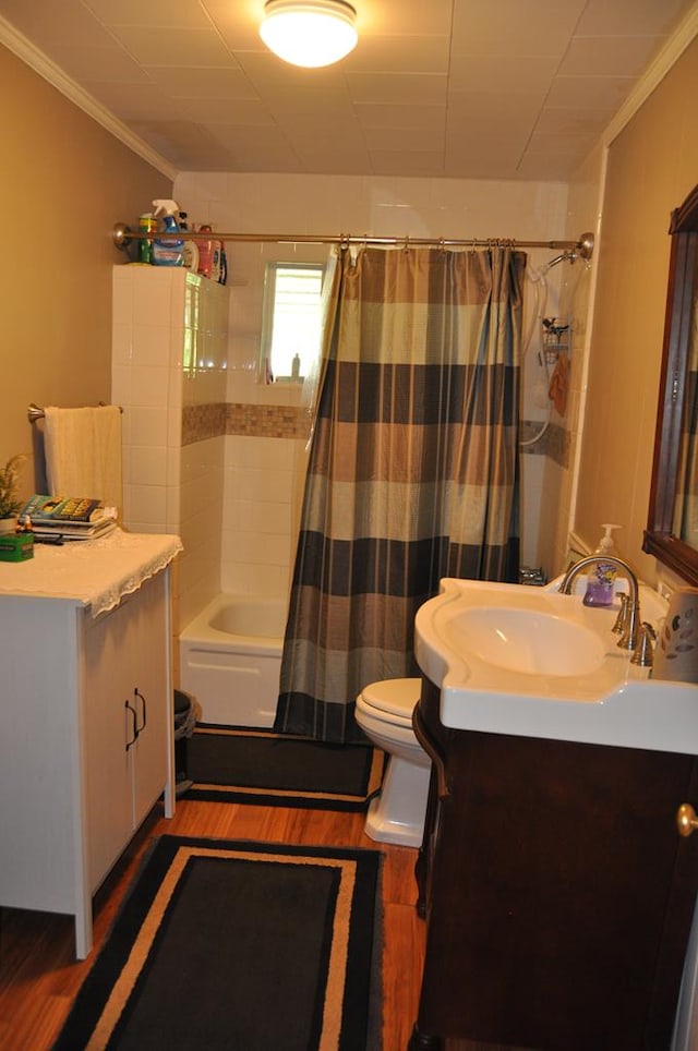 full bathroom featuring hardwood / wood-style floors, shower / bath combination with curtain, ornamental molding, and vanity