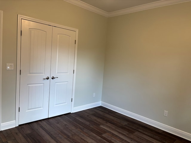 unfurnished bedroom featuring dark hardwood / wood-style flooring, crown molding, and a closet