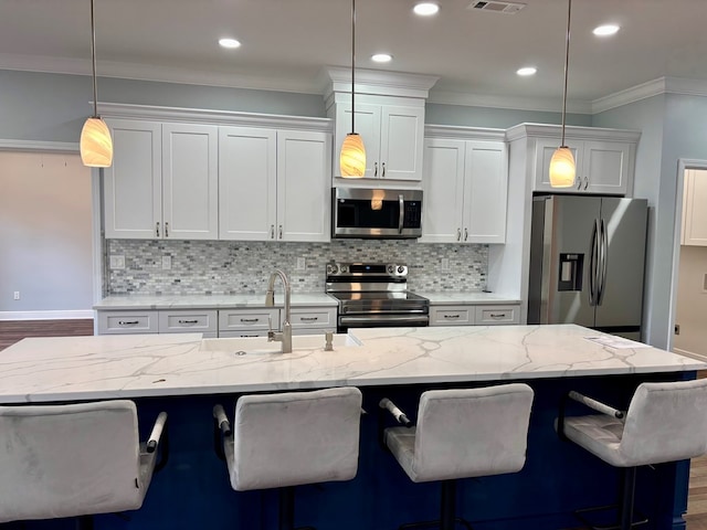 kitchen featuring hanging light fixtures, appliances with stainless steel finishes, sink, and a breakfast bar