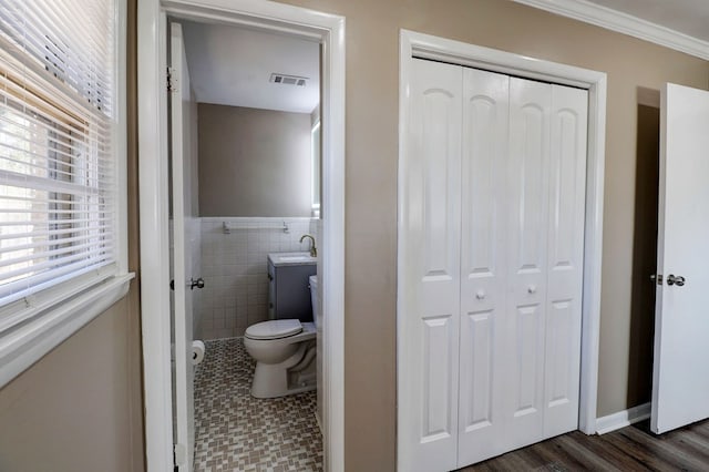 bathroom with toilet, hardwood / wood-style flooring, tile walls, ornamental molding, and sink