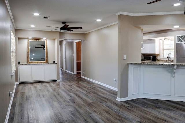 kitchen with crown molding, white cabinetry, hardwood / wood-style floors, and light stone counters