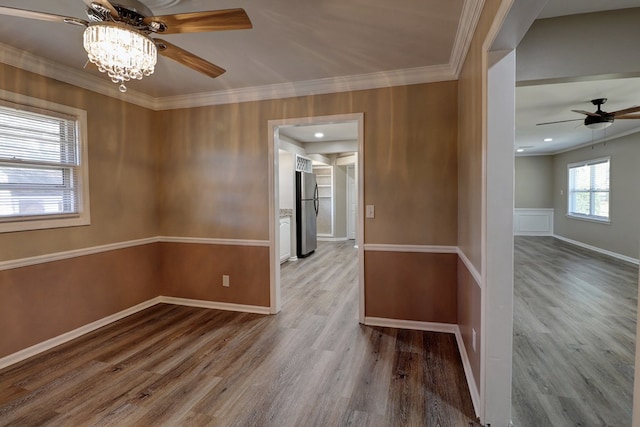 spare room with a notable chandelier, light hardwood / wood-style floors, and crown molding