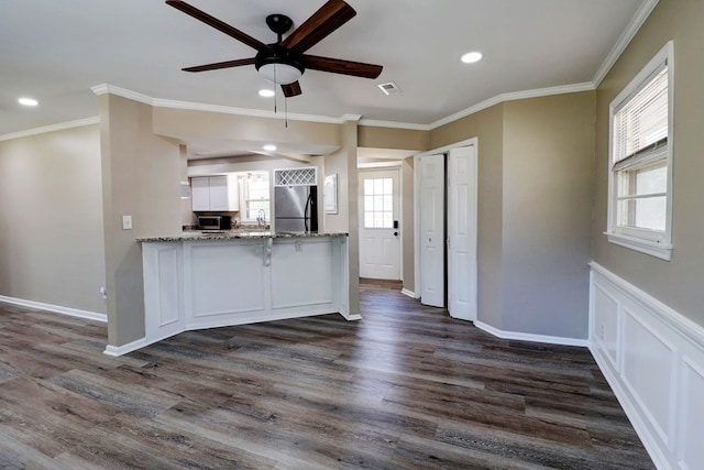 kitchen with white cabinets, crown molding, dark hardwood / wood-style floors, and stainless steel refrigerator