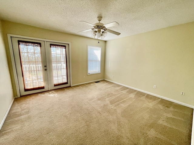 spare room with a ceiling fan, baseboards, carpet floors, french doors, and a textured ceiling