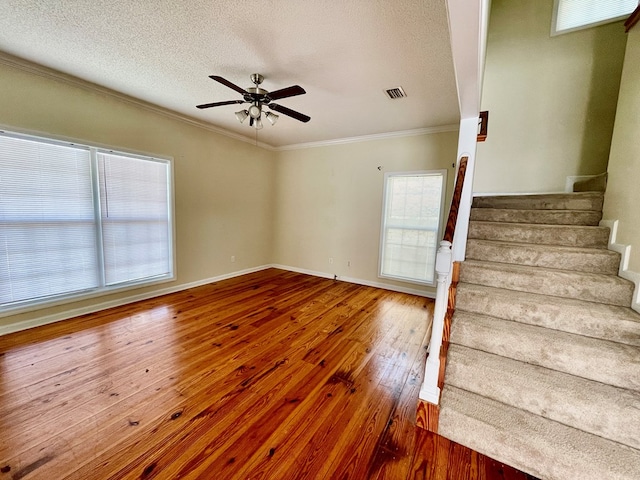 interior space featuring visible vents, hardwood / wood-style flooring, stairway, crown molding, and ceiling fan
