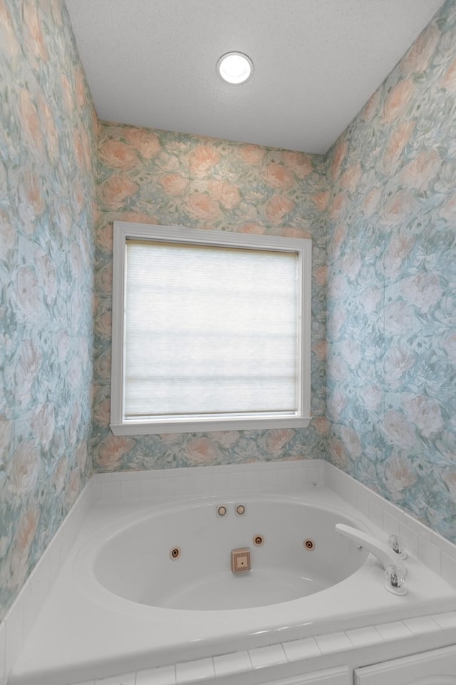 bathroom with a textured ceiling, a tub to relax in, and plenty of natural light