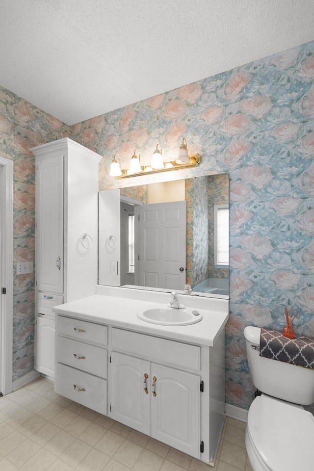 bathroom with vanity, toilet, and a textured ceiling