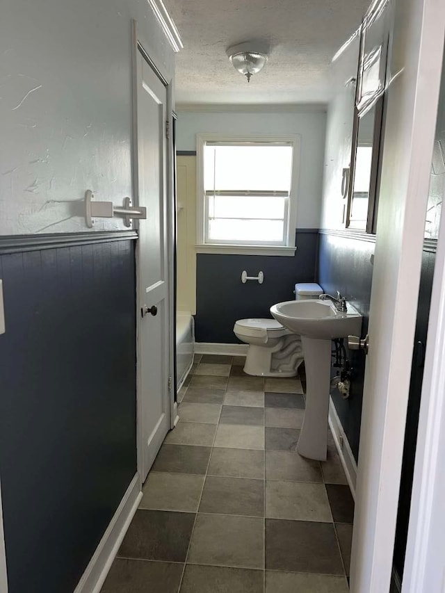 bathroom featuring toilet, a textured ceiling, and a sink
