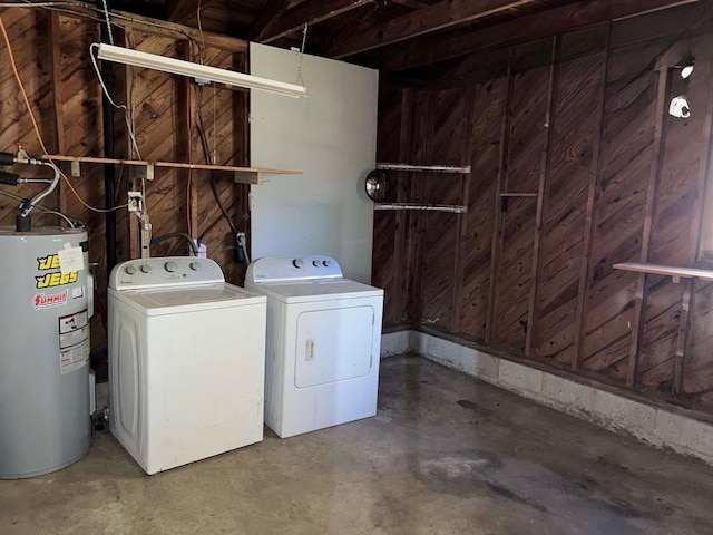 washroom featuring wood walls, laundry area, washer and dryer, and electric water heater