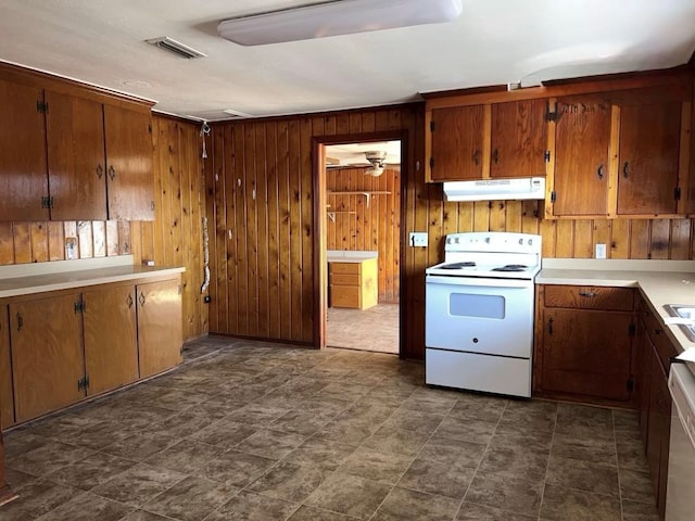kitchen featuring under cabinet range hood, light countertops, wooden walls, visible vents, and electric range