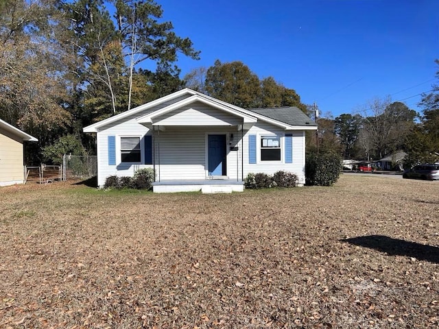 bungalow-style home featuring a porch, a front lawn, and fence