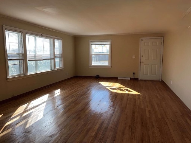 empty room featuring baseboards, wood finished floors, a baseboard radiator, and crown molding