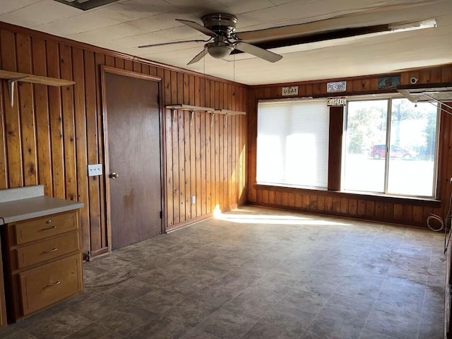 spare room featuring dark floors, wood walls, and ceiling fan