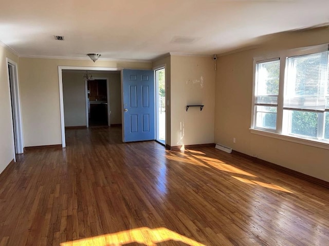 empty room featuring visible vents, baseboards, ornamental molding, and dark wood-style flooring