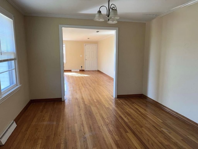 unfurnished room featuring a baseboard heating unit, baseboards, a notable chandelier, wood finished floors, and ornamental molding