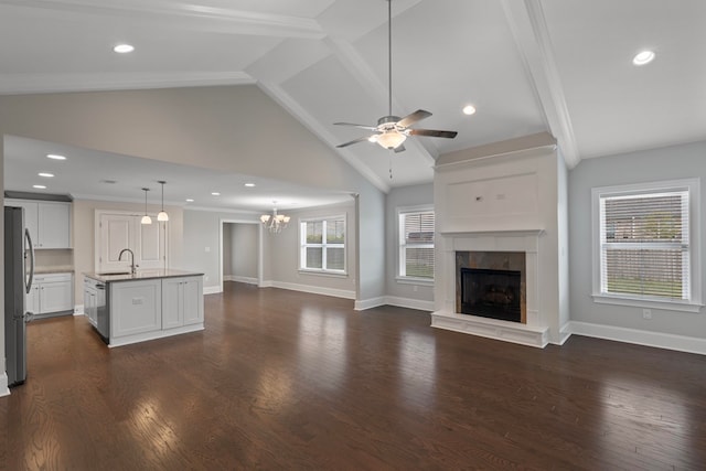 unfurnished living room featuring dark hardwood / wood-style flooring, plenty of natural light, ceiling fan with notable chandelier, and sink