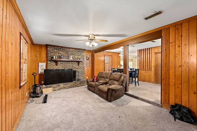 living area with a brick fireplace, visible vents, wood walls, and carpet flooring