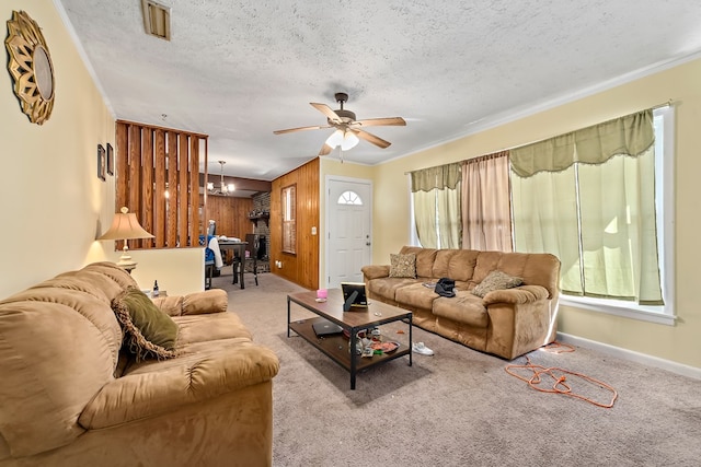 carpeted living room with ornamental molding, a textured ceiling, baseboards, and ceiling fan with notable chandelier