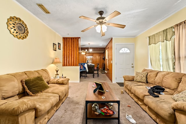 living room with a textured ceiling, ceiling fan with notable chandelier, visible vents, carpet, and crown molding