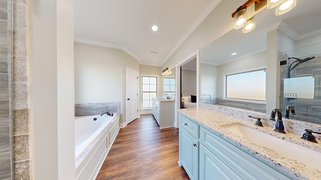 bathroom with ornamental molding, a tub, hardwood / wood-style floors, and vanity