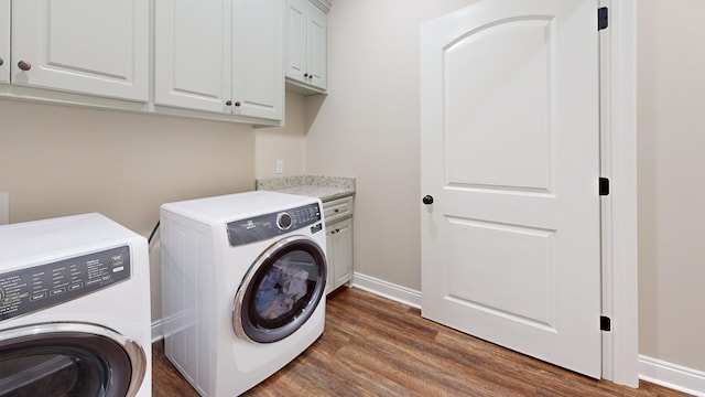 clothes washing area with cabinets, dark hardwood / wood-style floors, and washing machine and clothes dryer