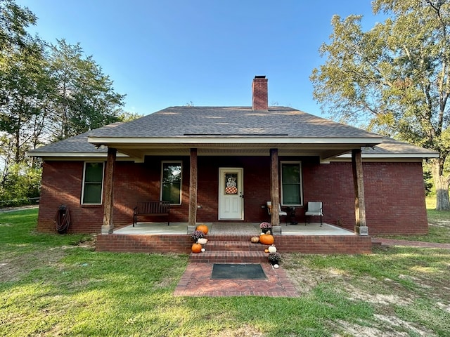 1456 State Highway 134 E, Headland, AL 36345 - back of property with covered porch, a chimney, roof with shingles, brick siding, and a yard