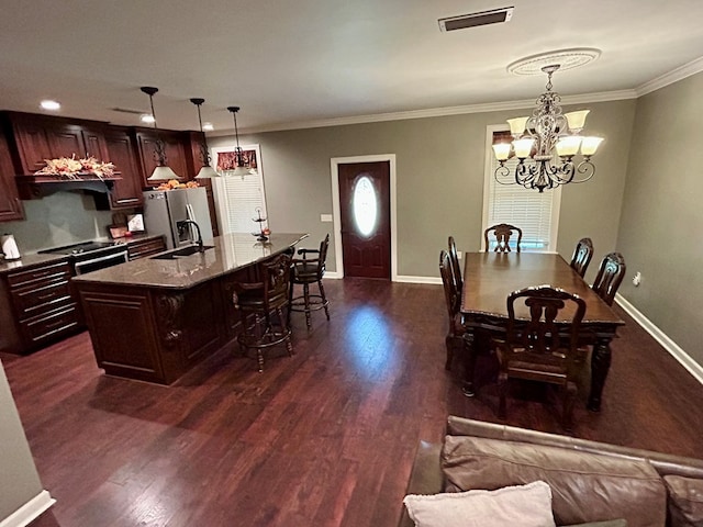 dining space with ornamental molding, dark hardwood / wood-style flooring, a chandelier, and sink