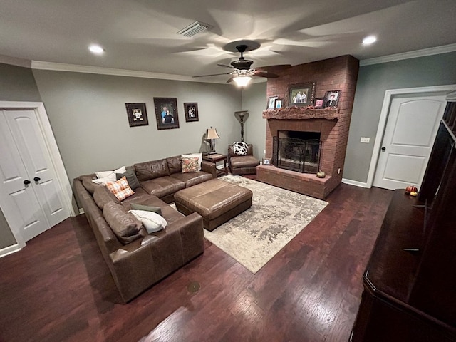 living room with dark hardwood / wood-style floors, ceiling fan, crown molding, and a brick fireplace