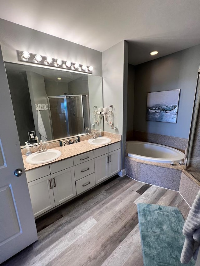 full bath with a sink, a bath, a stall shower, and double vanity
