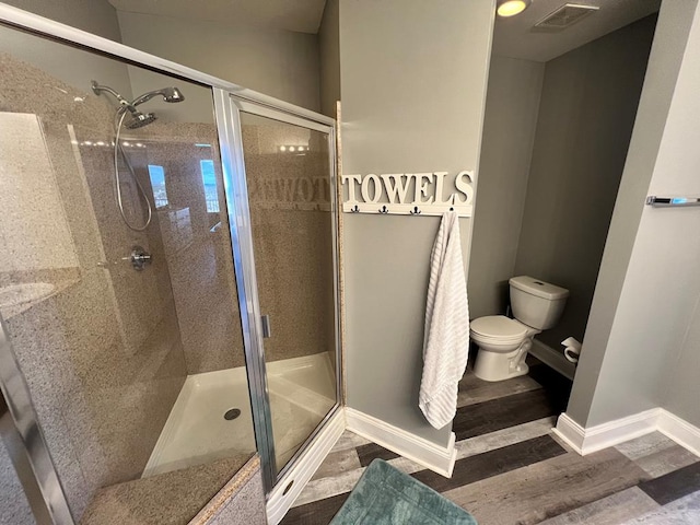 bathroom with visible vents, a stall shower, baseboards, and wood finished floors