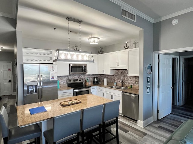 kitchen featuring visible vents, decorative backsplash, wood finished floors, a sink, and appliances with stainless steel finishes