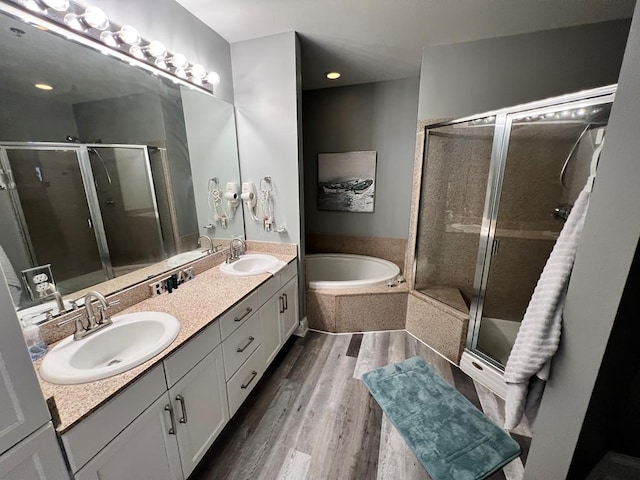 bathroom with a shower stall, a sink, a garden tub, and wood finished floors
