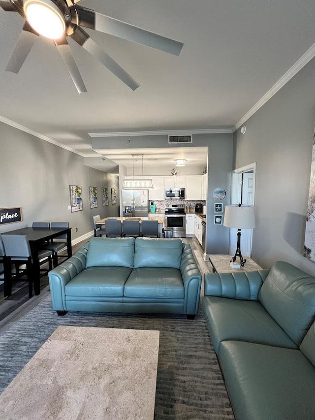living room with crown molding, a ceiling fan, and visible vents
