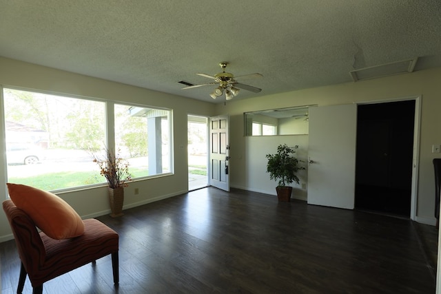 interior space featuring baseboards, dark wood-style floors, ceiling fan, and a textured ceiling