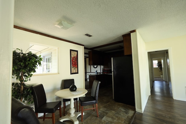 dining area with visible vents, a textured ceiling, baseboards, and dark wood finished floors