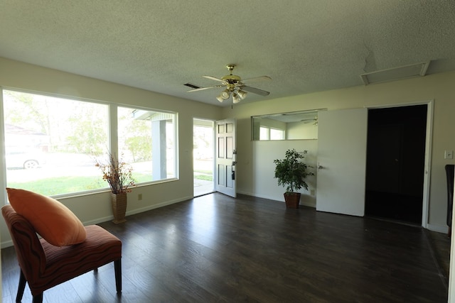 interior space with dark wood-type flooring, a textured ceiling, ceiling fan, and baseboards