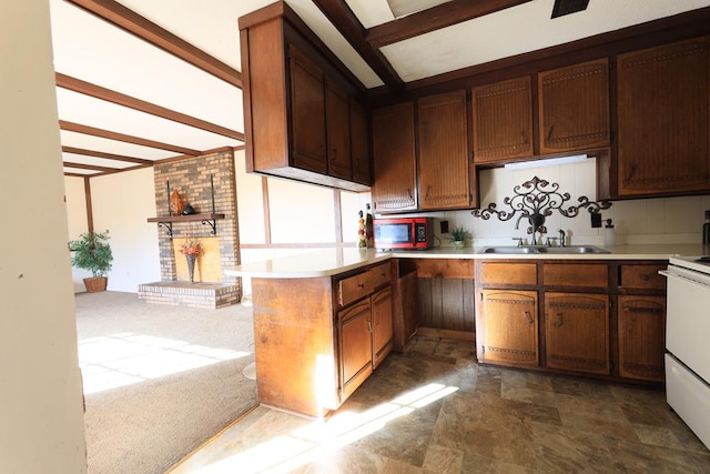 kitchen featuring stove, dark colored carpet, sink, a brick fireplace, and kitchen peninsula